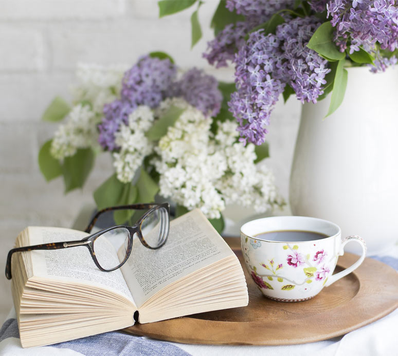 Brille auf Buch mit Blumen im Hintergrund