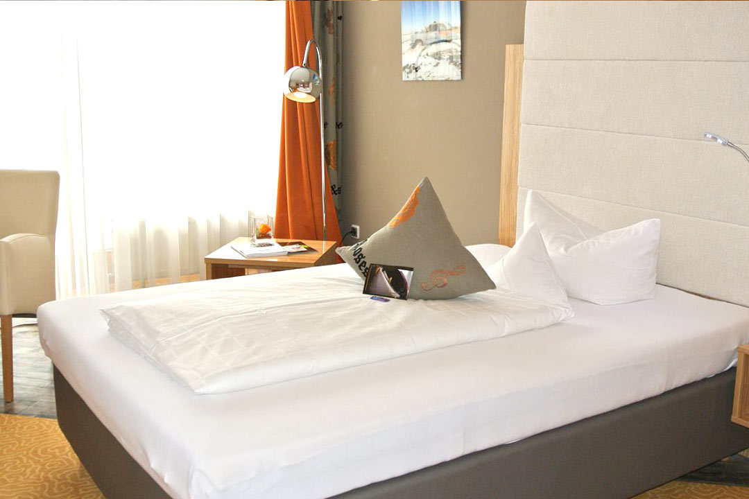 Einzelzimmer Premium - Modern eingerichtetes Hotelzimmer in Orange-Braun-Tönen