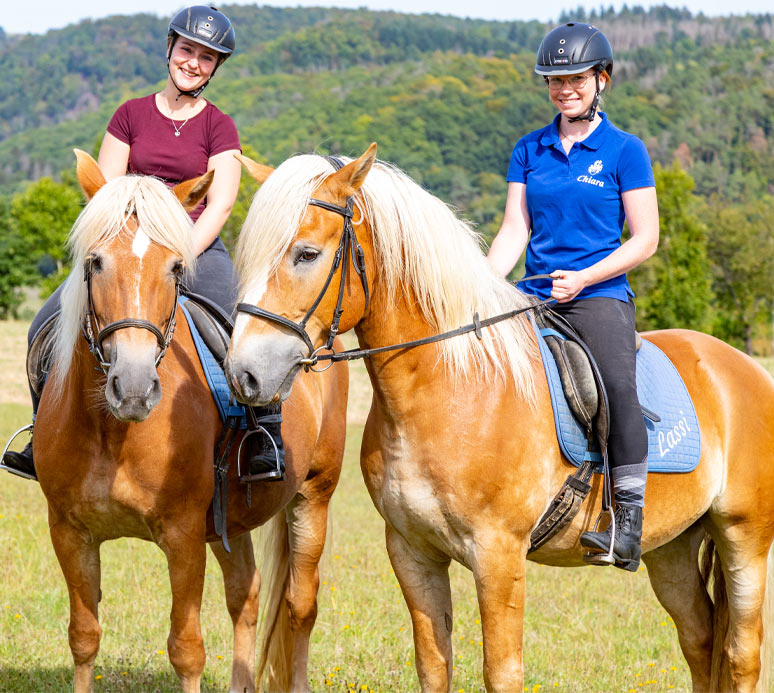 Les vacances à cheval de Freunds - Deux femmes assises sur des chevaux et souriant à la caméra