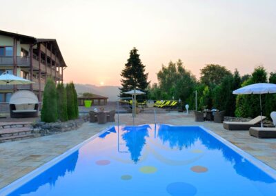 Hotel mit malerischem Pool und Liegen umgeben von Natur am Abend