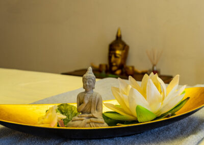 Dekorative Schale mit Buddhafigur und Lilie auf Tisch